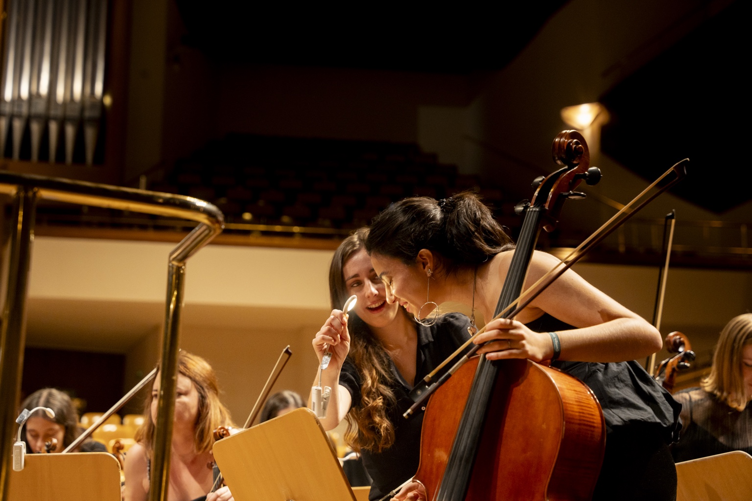 Dos jóvenes violonchelistas compartiendo un momento de complicidad